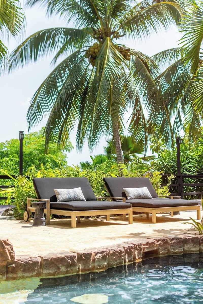 Double daybeds shaded by palms in the garden