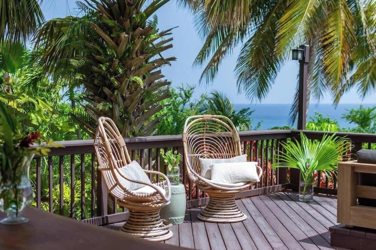 Wooden deck with chairs overlooking the ocean through palms